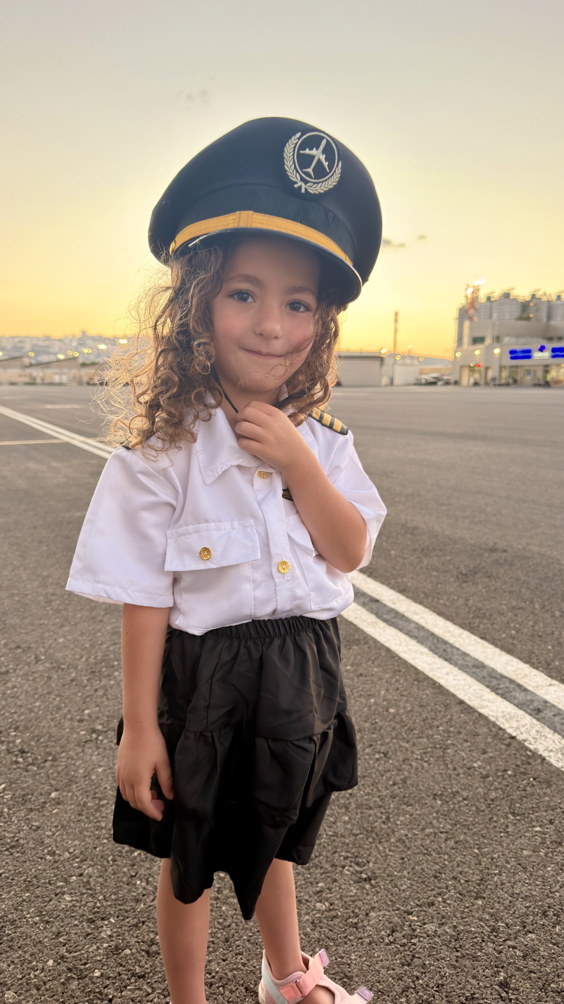 ילדה במדי טייס ליד המטוס בשעת שקיעה